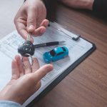Concept car rental. Close up view Hand of agent giving car key to customer after signed rental contract form.